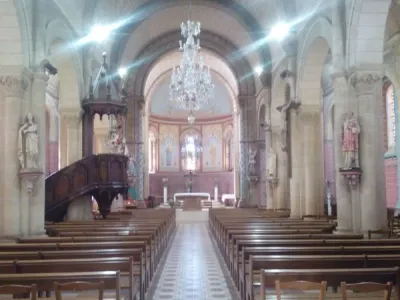 Éclairage intérieur d’une église avec lustre central et bancs en bois